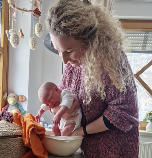 Hebamme Romy Leuteritz wäscht die Füße eines Neugeborenen während der Nachsorge in Zwickau